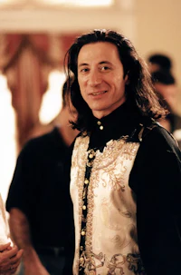 a man with long hair standing next to another man