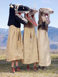 three people dressed in animal masks standing in a field